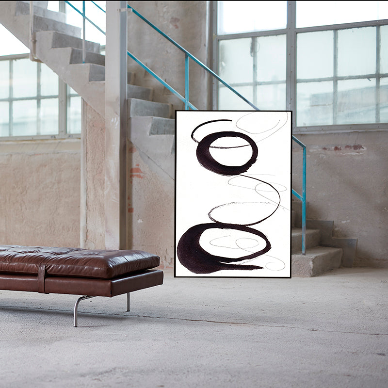 Abstract art piece on a wall in an industrial-style room with a brown leather bench.