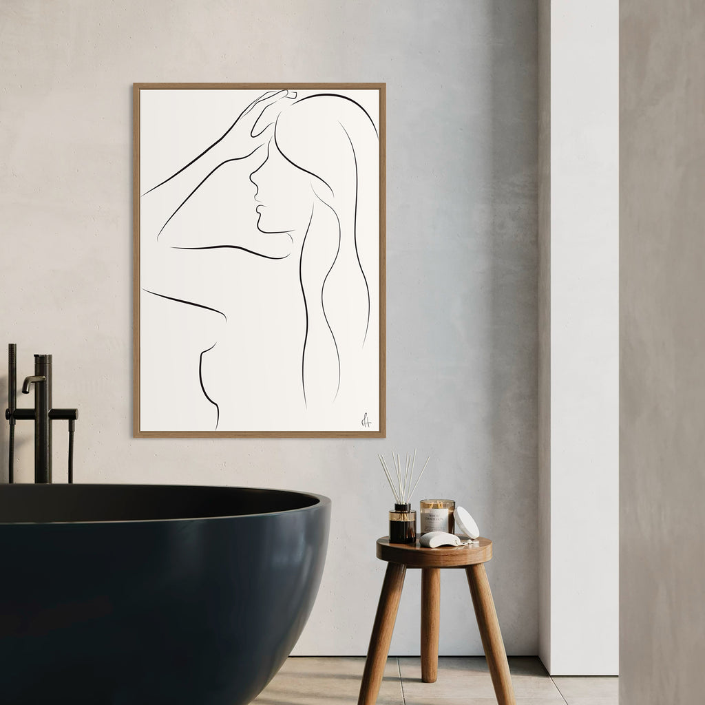 Minimalist line art of a woman's profile in a wooden frame on a bathroom wall.